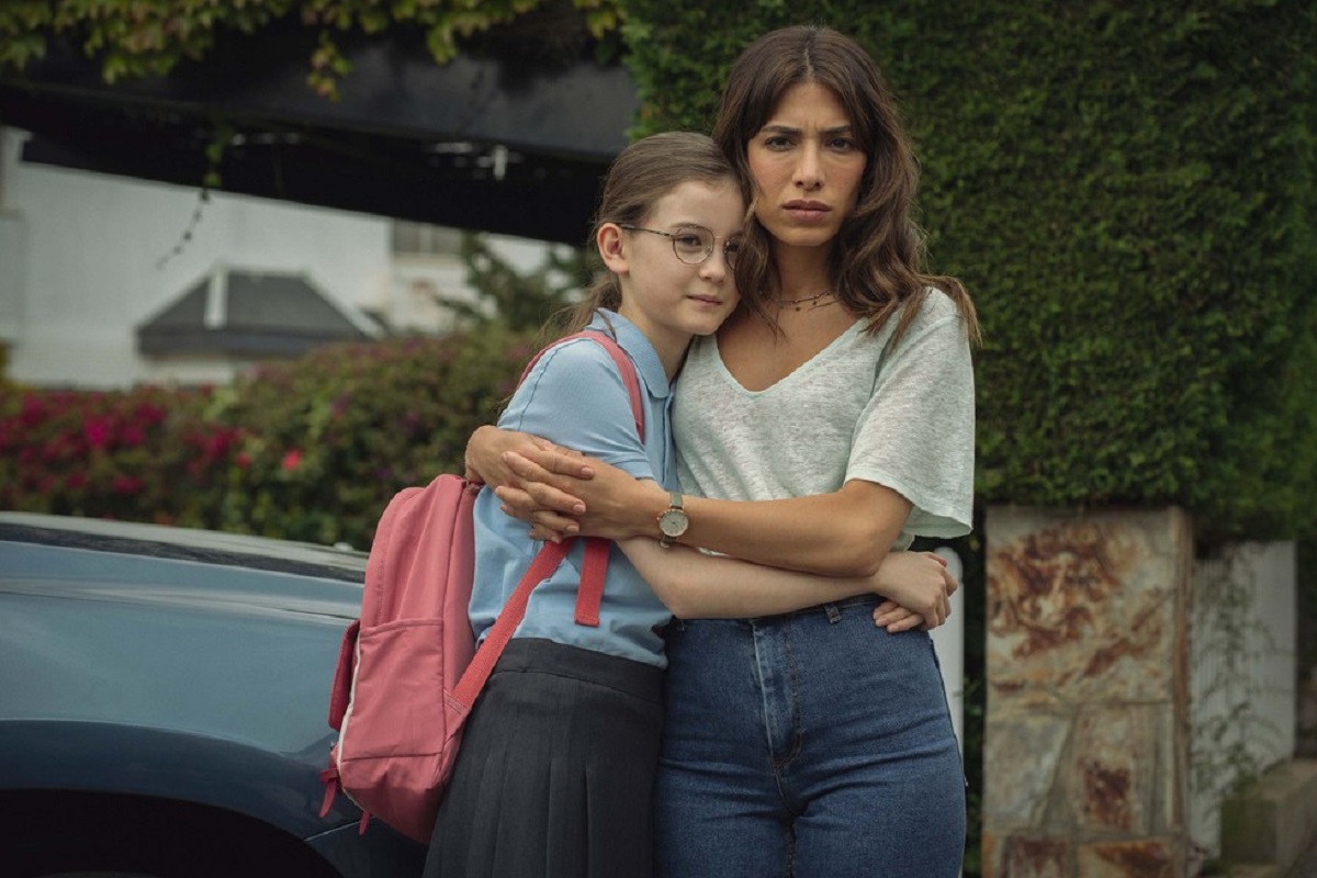 Quem é Erin Carter é a mais nova minissérie de ação de mistério da Netflix, que chegou fazendo barulho entre os fãs de um bom suspense. Ao longo dos 7 episódios da série, o espectador fica por dentro do passado de Erin envolvendo sua filha Harper, mas será que as duas conseguem ficar juntas no final?

Bom, é isso que a gente vai te explicar a seguir. Confira!

O que acontece no final de "Quem é Erin Carter"?

Atenção, spoilers da série a seguir.

Na série, desde que Erin precisa agir para defender sua filha de bandidos em um supermercado, ela vê sua vida virar de cabeça pra baixo, e vários fatos de seu passado misterioso voltam. Incluindo a verdade sobre sua filha, Harper.

No quarto episódio da série o público descobre que Erin não é a mãe biológica de Harper, e que enquanto trabalhava como agente secreta de uma organização britânica, ela conhecer a verdadeira mãe da menina, Lena.

Infiltrada na gangue da mãe de Harper, quando um tiroteio entre sua agência e a gangue começa, Erin viu Lena ser baleada, e por isso pegou Harper e decidiu fugir com a criança.

Nos anos que se seguiram, Erin viveu em anonimato com a filha e o marido, porém, os acontecimentos após o assalto ao mercado trouxeram tudo à tona, incluindo que Lena na verdade sempre esteve viva e na prisão.

Harper e Erin ficam juntas no final?

Após fugir da prisão, Lena consegue rastrear Erin e a confronta. Quando Erin lhe oferece o ouro roubado em troca de que Lena deixe ela e Harper em paz, a verdadeira mãe da menina atira em Erin.

Disposta a contar tudo para sua filha, Lena acaba sendo sequestrada antes de juntar coragem para fazer isso. Quando ela e seu sequestrado, Daniel, descobrem que Erin não está morta após o tiro, ele ordena a seus capangas que matem a mulher, o marido e Harper.

Lena consegue fazer um acordo com Daniel para trazer Erin para ele contanto que ele livre Harper. Após finalmente encontrar sua filha, e ser renegada por ela, Lena a vê ser sequestrada por Daniel.

No final, Lena e Erin precisam unir forçar para conseguir salvar Harper, e em meio a isso, Lena acaba morrendo, se sacrificando para que sua filha sobreviva e tenha uma vida feliz ao lado da mãe e do pai que a criaram.

Assim, no final de Quem é Erin Carter, Harper e Erin ficam juntas, com a família se reunindo para férias no final da temporada.

CONFIRA Também: Pretendente Surpresa vai ganhar uma 2 temporada na Netflix?